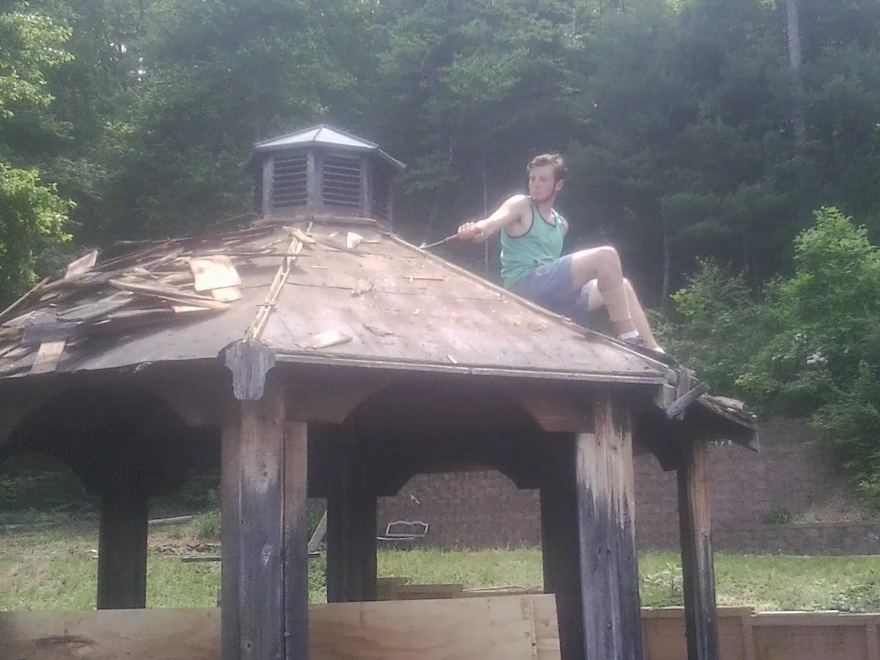 Tearing the old roof off a wooden gazebo before new shakes in Rienzi