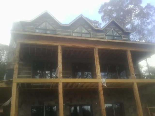 Dormers and porch framing on a large log home under construction — Roof Coating work by our crew in Rienzi