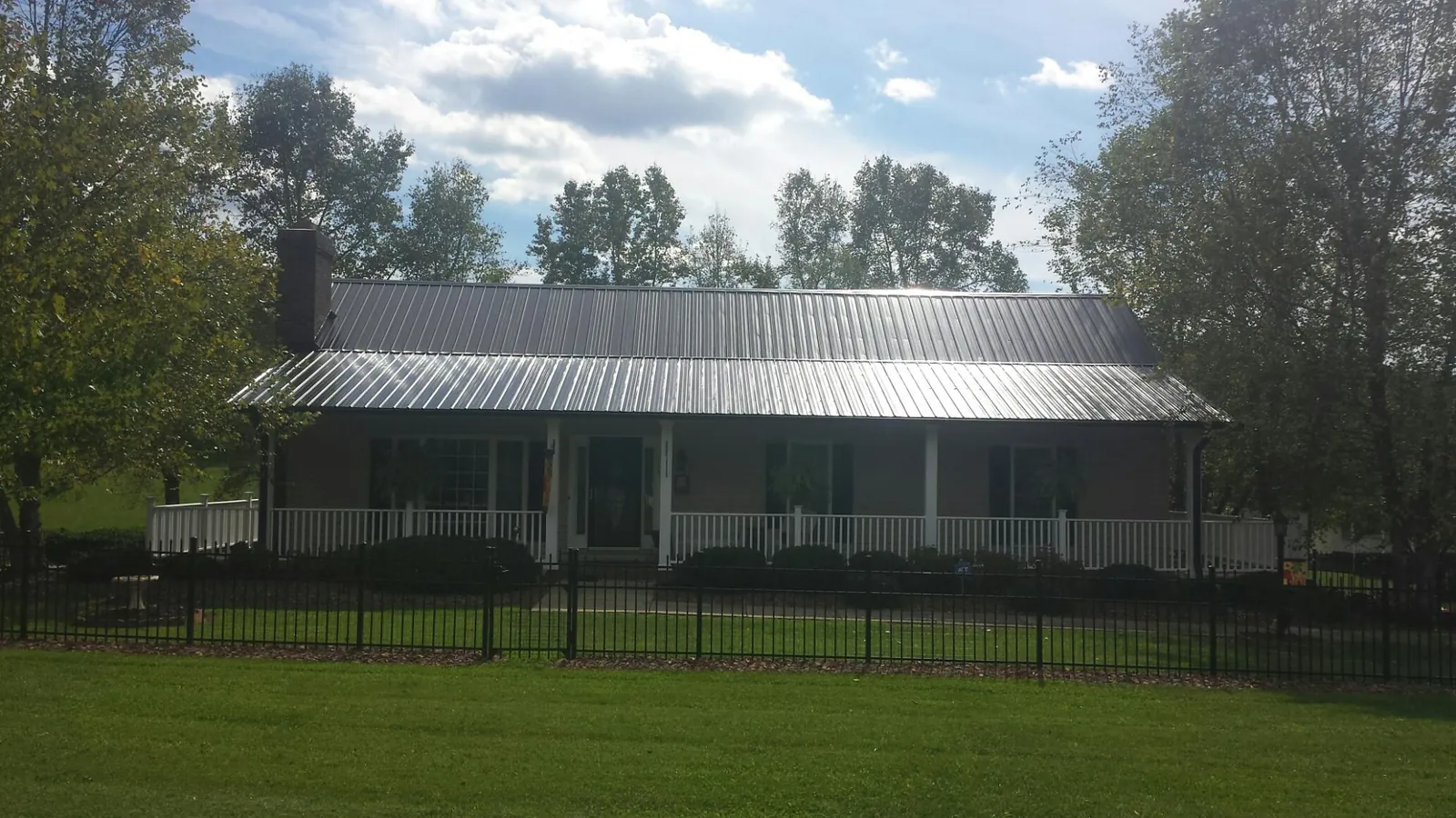 Gray metal roof on a brick ranch with a full width front porch — Gutter Guard Installation work by our crew in Rienzi