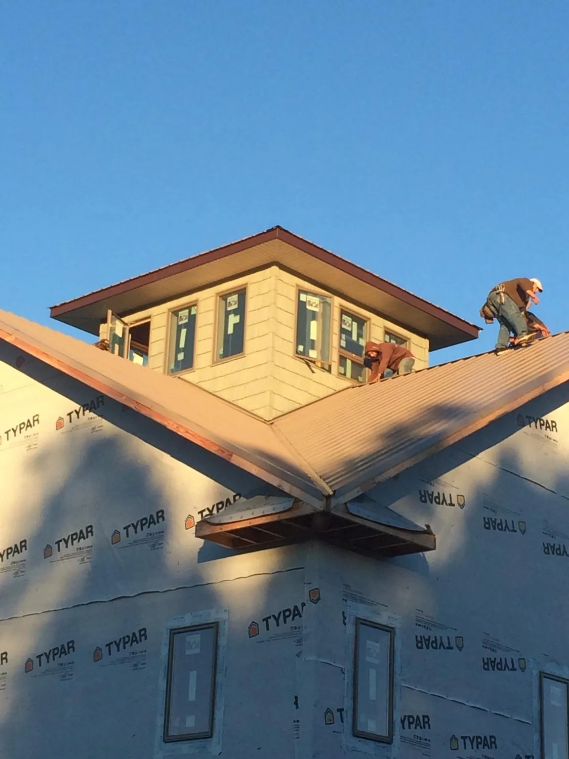 Roofers working around a rooftop cupola on a new metal roof at sunset — Roof Waterproofing in Rienzi by Roofing Brothers